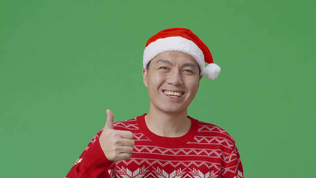 산타 모자와 빨간 스웨터를 입은 남자가 엄지손가락을 올리고