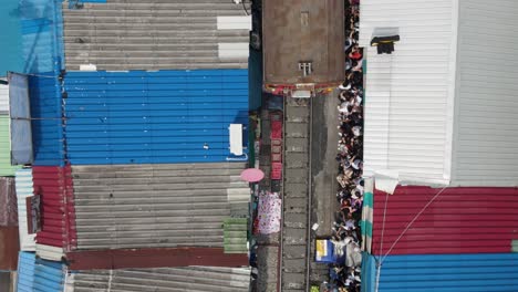 aerial top-down view: train arrival at mae klong railway market, thailand