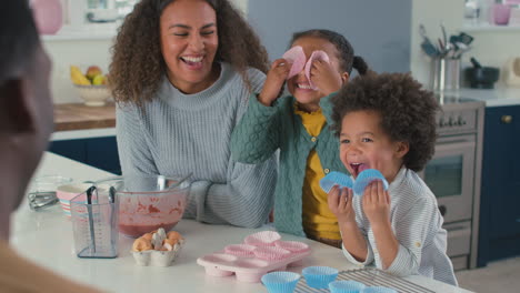 Familia-Con-Niños-En-La-Cocina-Divirtiéndose-Con-Cajas-Mientras-Hornean-Pastelitos.