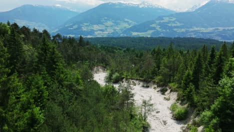 drone flies upward over dried up river in the mountains