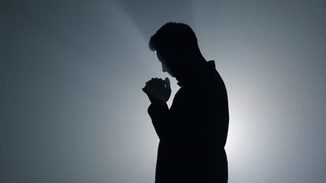 어 ⁇  속에서 하느님의 축복을 구하는 실루 ⁇  남자. 실내에서 기도하는 남성.