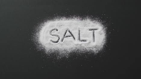 Animation-of-salt-text-written-in-salt-on-black-background