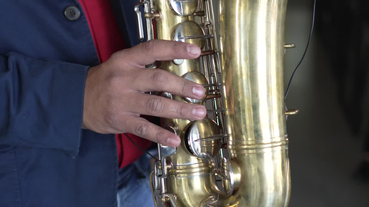 Mani di un musicista che suona il sassofono in un ristorante