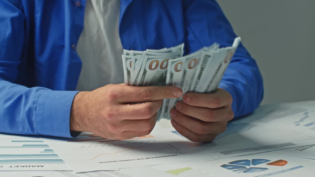 un primer plano de un hombre de negocios contando dinero y golpeando su puño en la mesa.