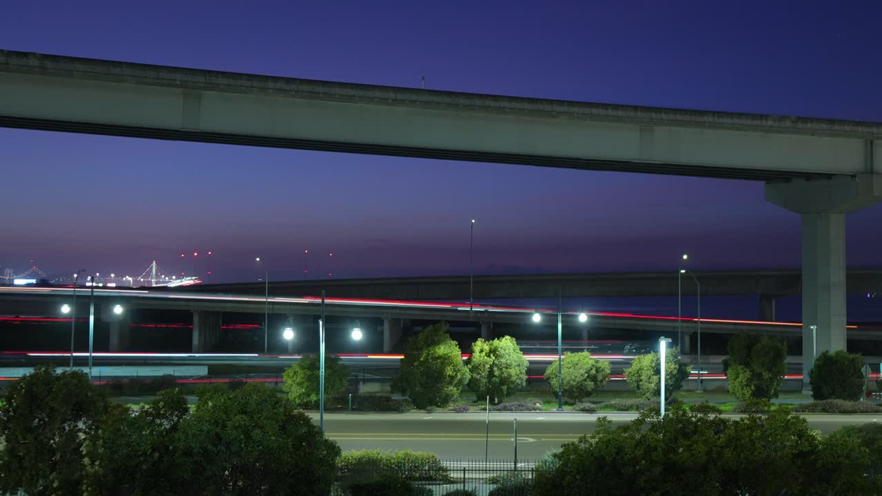 Time-lapse motion transforms I-80 and I-580 into glowing channels of activity, with Emeryville’s urban backdrop adding depth to the continuous flow of East Bay traffic patterns at night