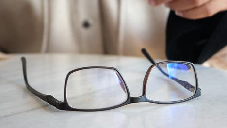 woman adjusting her glasses at a cafe