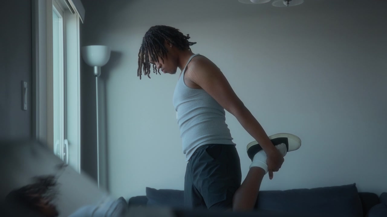 Young man exercising at home next to a window