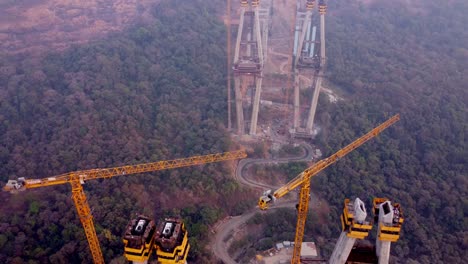 Industrial crane towers in road construction site in forest, Mumbai Pune Expressway construction site, Lonavala, Maharashtra, drone, revealing
