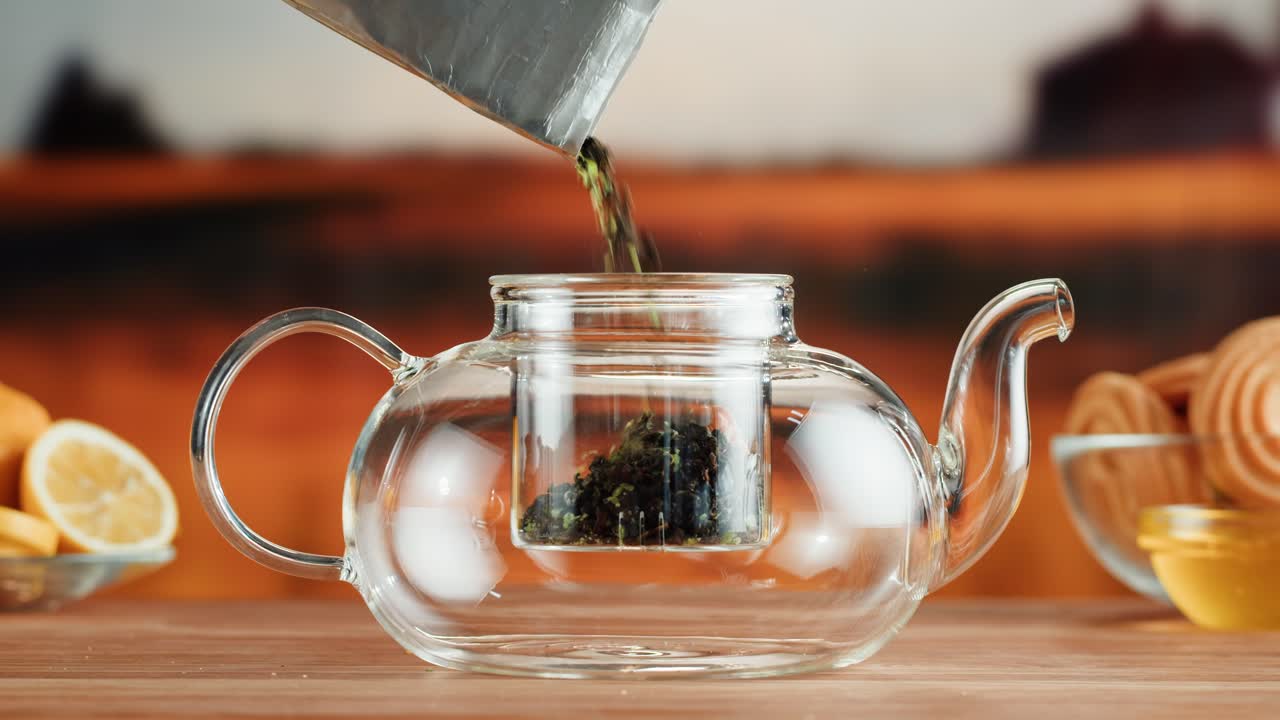 vertiendo hojas de té en una tetera de vidrio