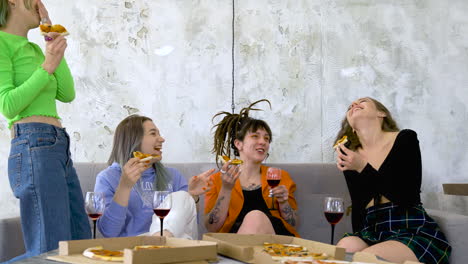 happy female friends eating pizza, drinking wine and talking at home 1