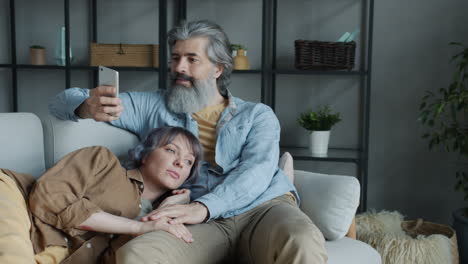 couple relaxing on couch, watching mobile phone