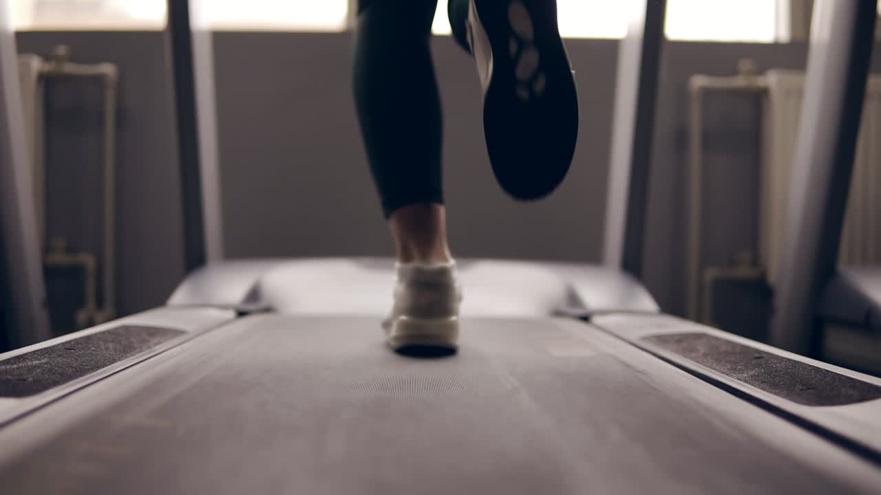 Slow motion footage of supposedly female legs in sneakers running on treadmill.