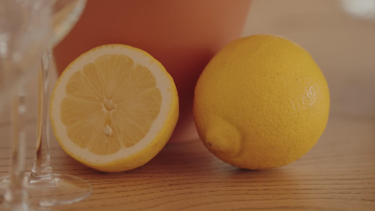 Whole lemon and half lemon displayed on wooden surface