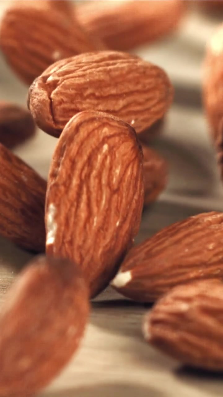 Des amandes tombant au ralenti sur une surface en bois.