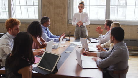 female boss addressing colleagues in a boardroom meeting