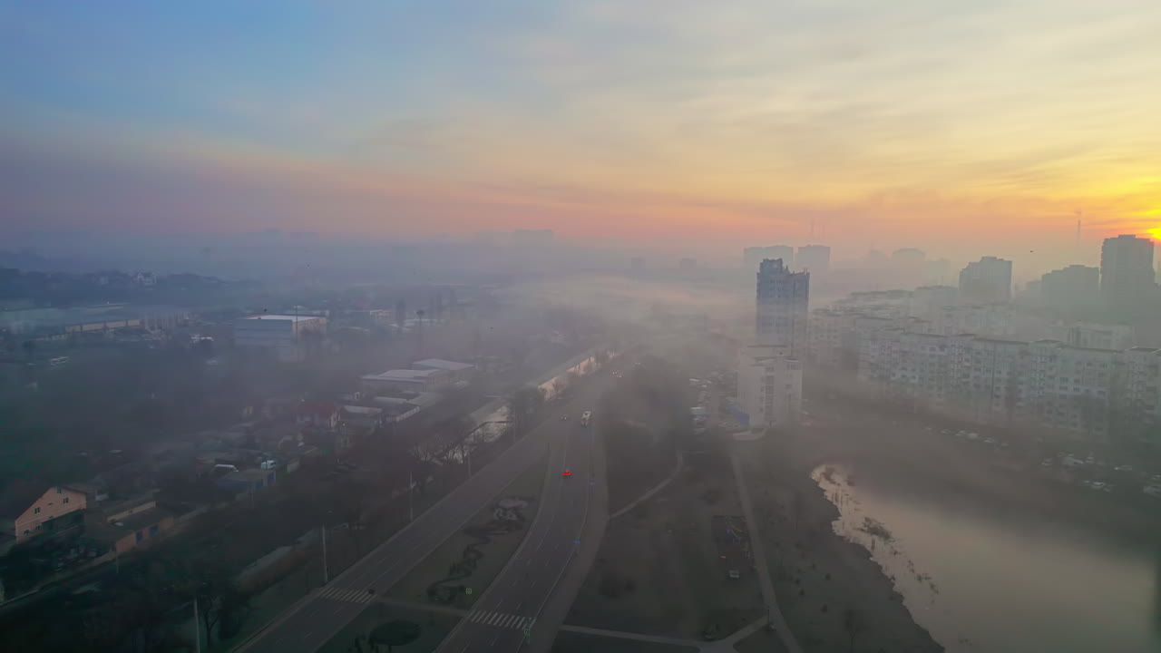 Aerial drone view of Chisinau at sunrise, Moldova. View of the city with fog in the air, multiple buildings, roads, lake, bare trees