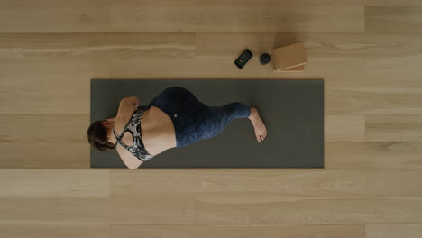 Vista-Superior-De-Una-Mujer-De-Yoga-Practicando-Una-Intensa-Pose-De-Estiramiento-Lateral-En-Un-Estudio-De-Ejercicios-Disfrutando-De-Un-Estilo-De-Vida-Saludable,-Practicando-Meditación-En-Una-Colchoneta-De-Ejercicios.