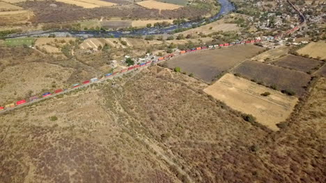 above-shot-of-several-train-wagons-on-a-railroad-track-passing-through-a-town-during-the-daytime