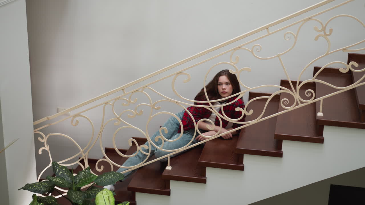 una mujer infeliz se apoya en la escalera de la mansión. una mujer con ropa casual tiene una experiencia traumática en la residencia. necesita terapia psicológica.