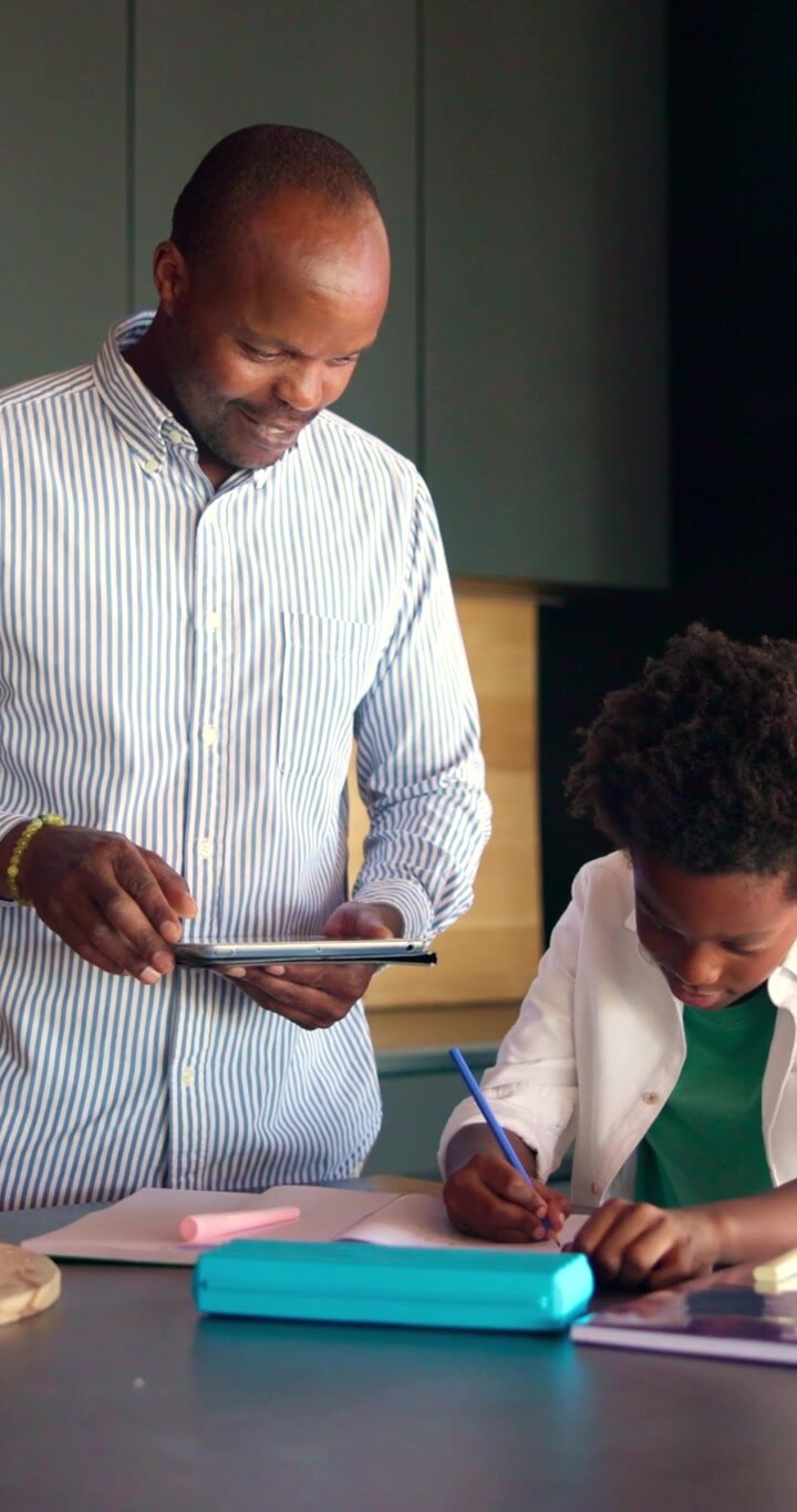 Father Helping Son With Homework Using Tablet at Home