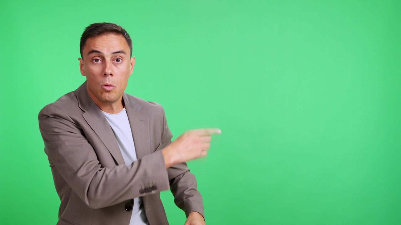 Surprised man pointing with excitement on green screen