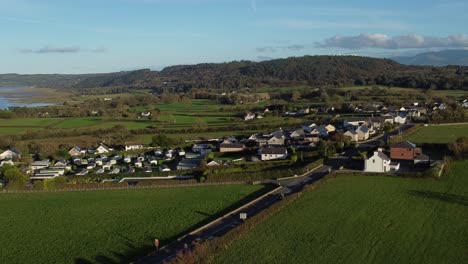 aerial view orbiting over small town welsh community farmland with snowdonia mountain range on the horizon