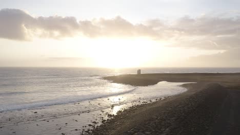 vívido amanecer en la costa sur de islandia con terraplenes artificiales y faro