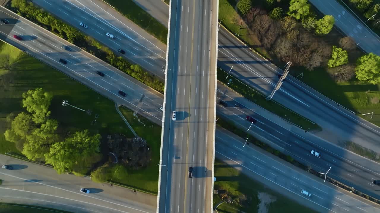 Aerial top down of traffic scene on Multi lane Highway and interstate road. Bridge with crossing cars. Spring day with green trees. American suburb district.
