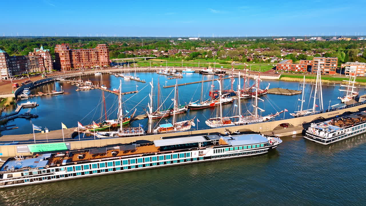 Diverse water transport at the berths in the port. Sunny marina of Lelystad, the Netherlands. Green cityscape with beautiful buildings at backdrop. Aerial view.
