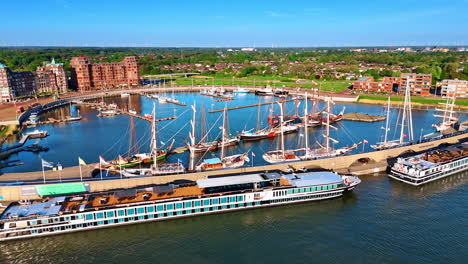diverse water transport at the berths in the port. sunny marina of lelystad, the netherlands. green cityscape with beautiful buildings at backdrop. aerial view.