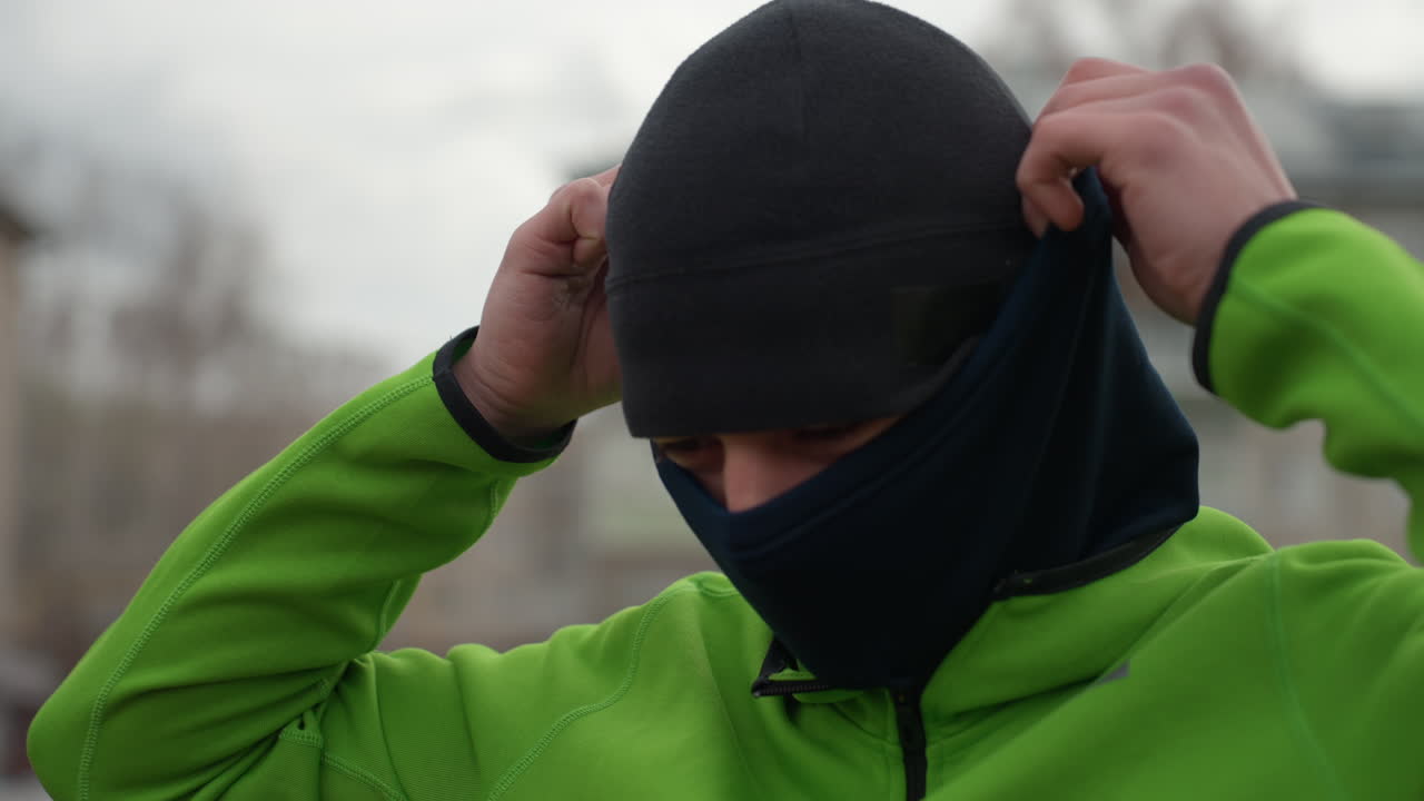 hombre ajustando su equipo antes de entrenar, hombre caucásico asegurándose de que la ropa sea perfecta para entrenar al aire libre con frío, atleta masculino haciendo los últimos ajustes al equipo antes de la sesión de entrenamiento en climas fríos