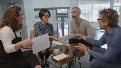 middle aged business people discussing papers in coworking room