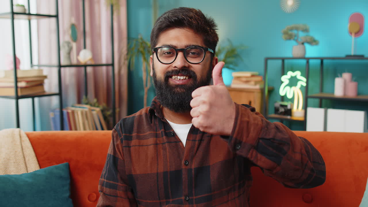 joven indio feliz mirando con aprobación a la cámara muestra los pulgares hacia arriba como un signo positivo buenas noticias