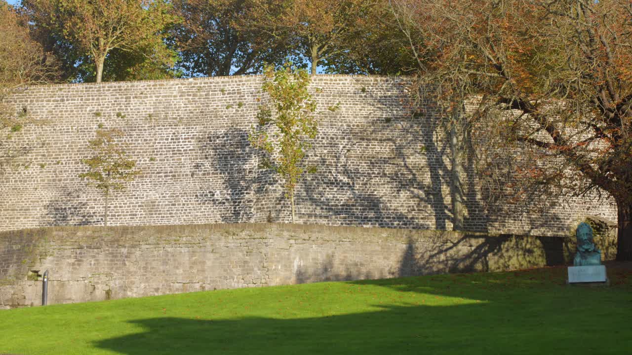 Static shot of tall stone wall and green grass at historic castle in Boulogne-sur-Mer, France
