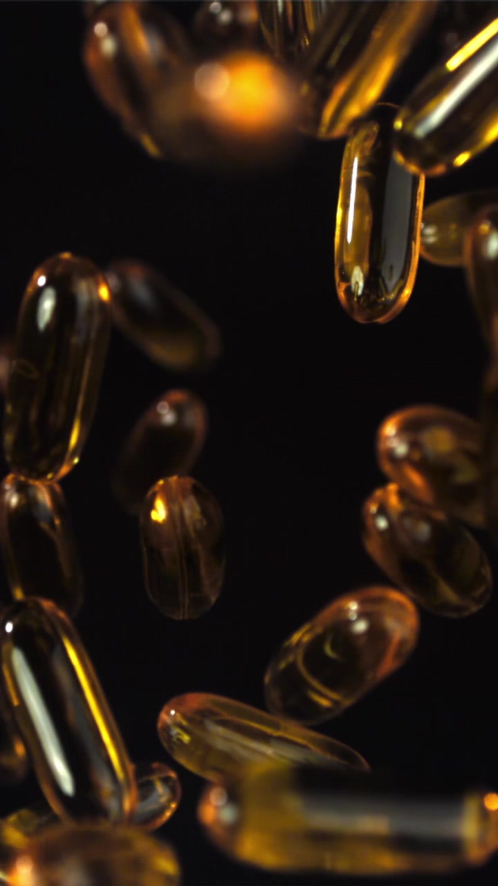 Capsule dorate di olio Omega 3 che fluttuano al rallentatore