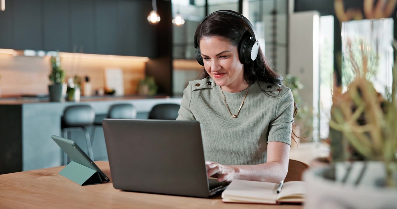 Smilende kvinde arbejder på bærbar computer på hjemmekontoret