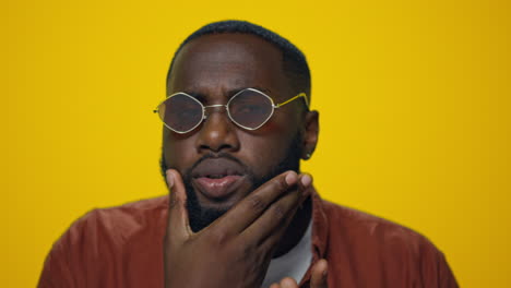 Retrato-De-Un-Hombre-Afroamericano-Serio-Revisando-La-Barba-Sobre-Fondo-Amarillo.