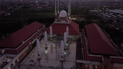 Circling close up drone shot of the great Mosque of Central Java (MAJT) in suset time. Th sun is orange and the weather is cloudy. It have some pillars and some umbrela that is closed