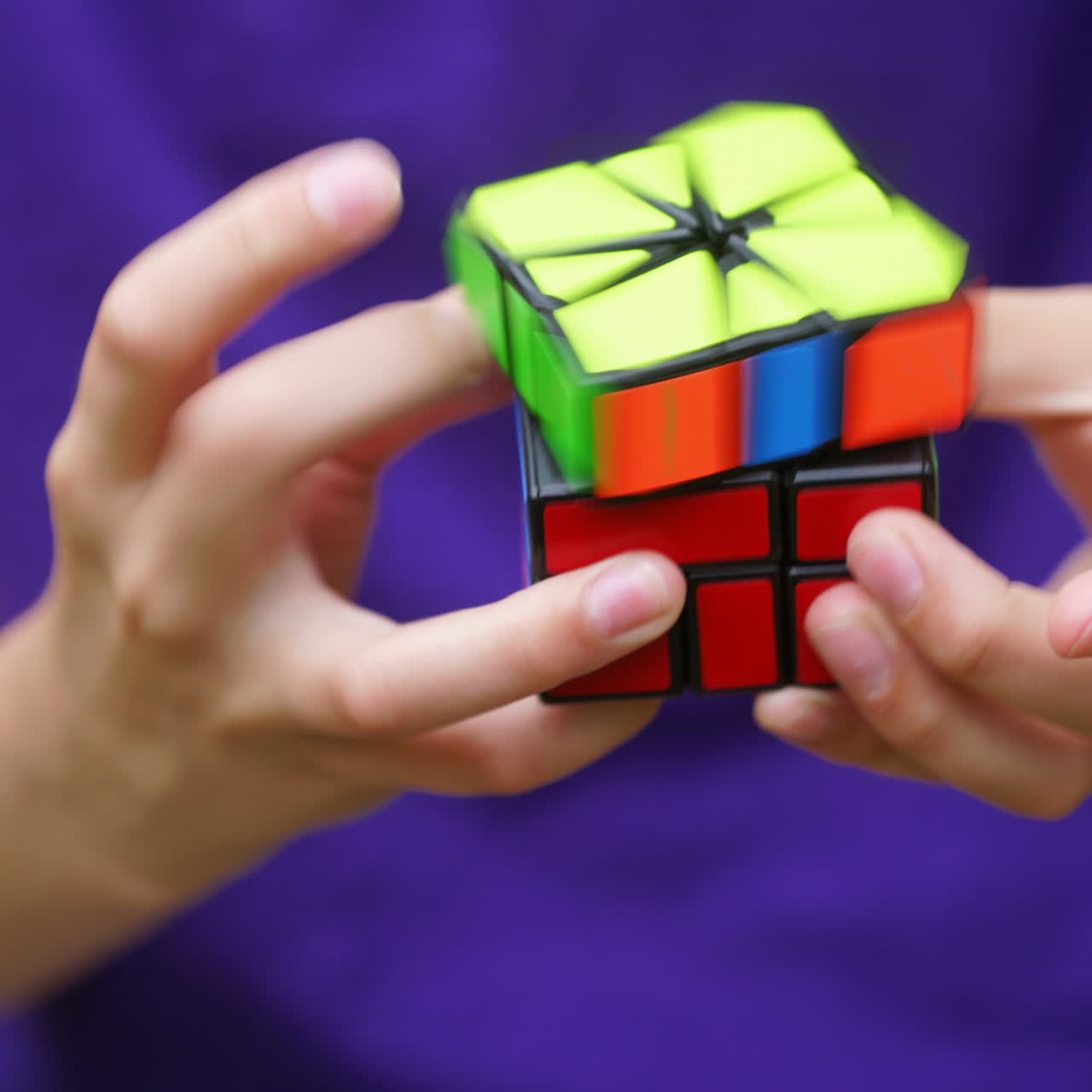 Boy's hands solving Rubik's Cube. Clever child holding Rubiks cube and doing quickly interesting puzzle game. Close-up of colorful cube in kid's hands.