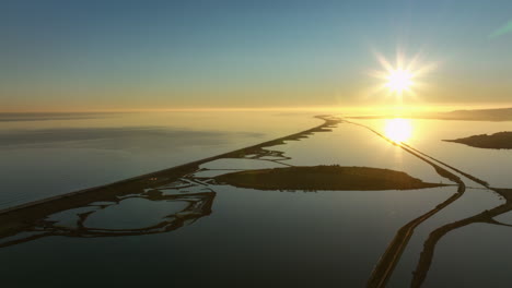 A-breathtaking-aerial-view-of-a-sunset-illuminating-a-meandering-coastal-road