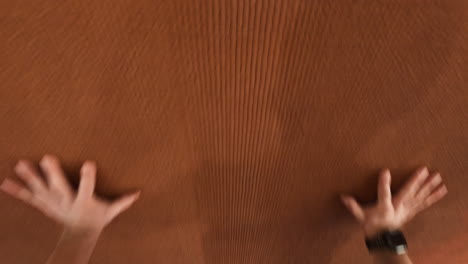 human hands pressing against a textured brown surface, with varying degrees of blur and abstraction