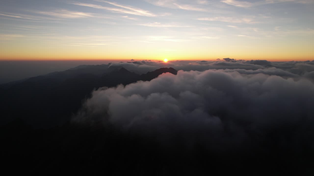 A sunrise above clouds with mountain peaks, evoking tranquility and awe