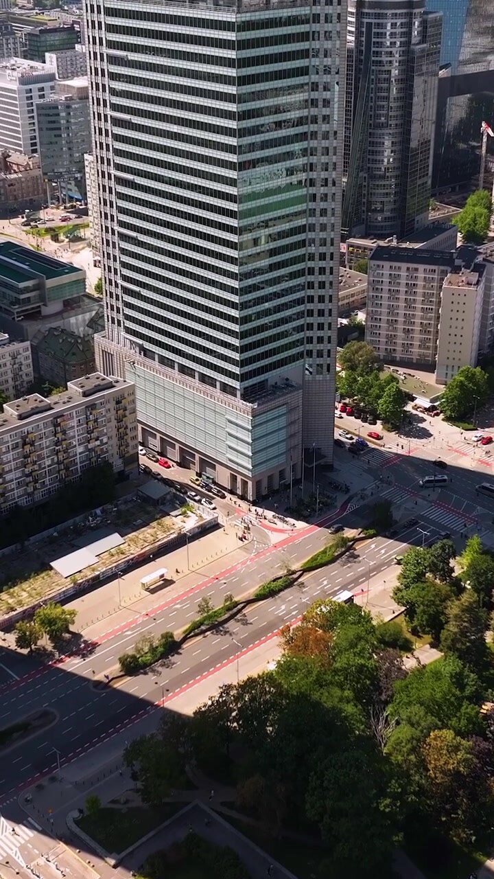 Distrito moderno del centro de Varsovia, Polonia, mostrando rascacielos, parques verdes y tráfico urbano en un día soleado. Metraje de paisaje urbano aéreo. Vídeo vertical