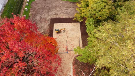 construction site surrounded by vibrant autumn trees in a park, aerial view