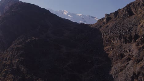 Cinematic-drone-footage-from-Huancayo,-Peru,-reveals-snow-covered-Huaytapallana-mountains-behind-rocky-hills-during-the-morning-hours