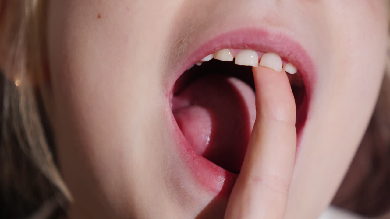 소녀는 곧 빠질 젖니로 손가락을 흔들고 있다