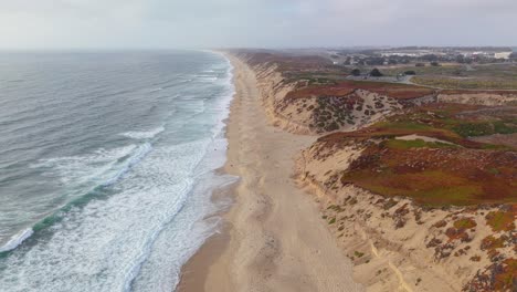 a wide static aerial shot shows fort ord beach where the gentle surf meets untouched sands beneath a glowing sky.