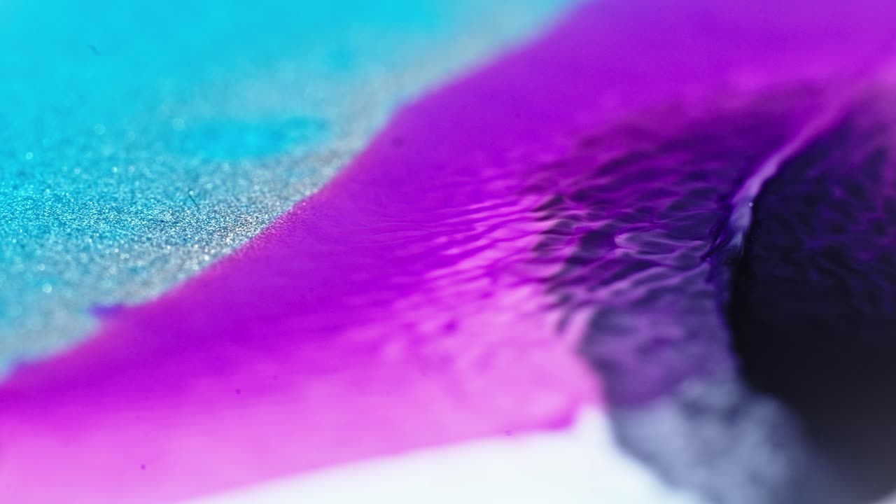 tinta rosa y azul que fluye en el agua con brillo, formando un patrón abstracto vibrante en un fondo blanco