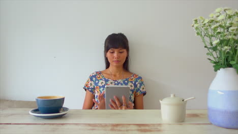 Attractive-Asian-girl-siting-in-coffee-shop-and-work-browsing-using-tablet