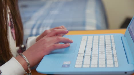 un primer plano de las manos de una joven mientras usa el trackpad en una computadora portátil en su habitación